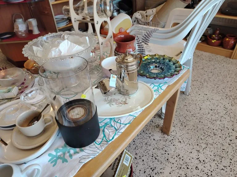 Töpinän torin pöydällä on esillä astioita, koriste-esineitä, lamppu ja muuta kodintavaraa.